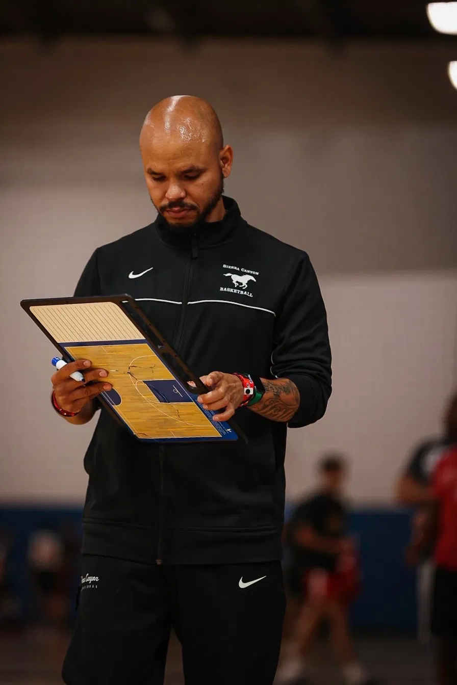 Coach Sandy studying a clipboard during training in the Sierra Canyon gym