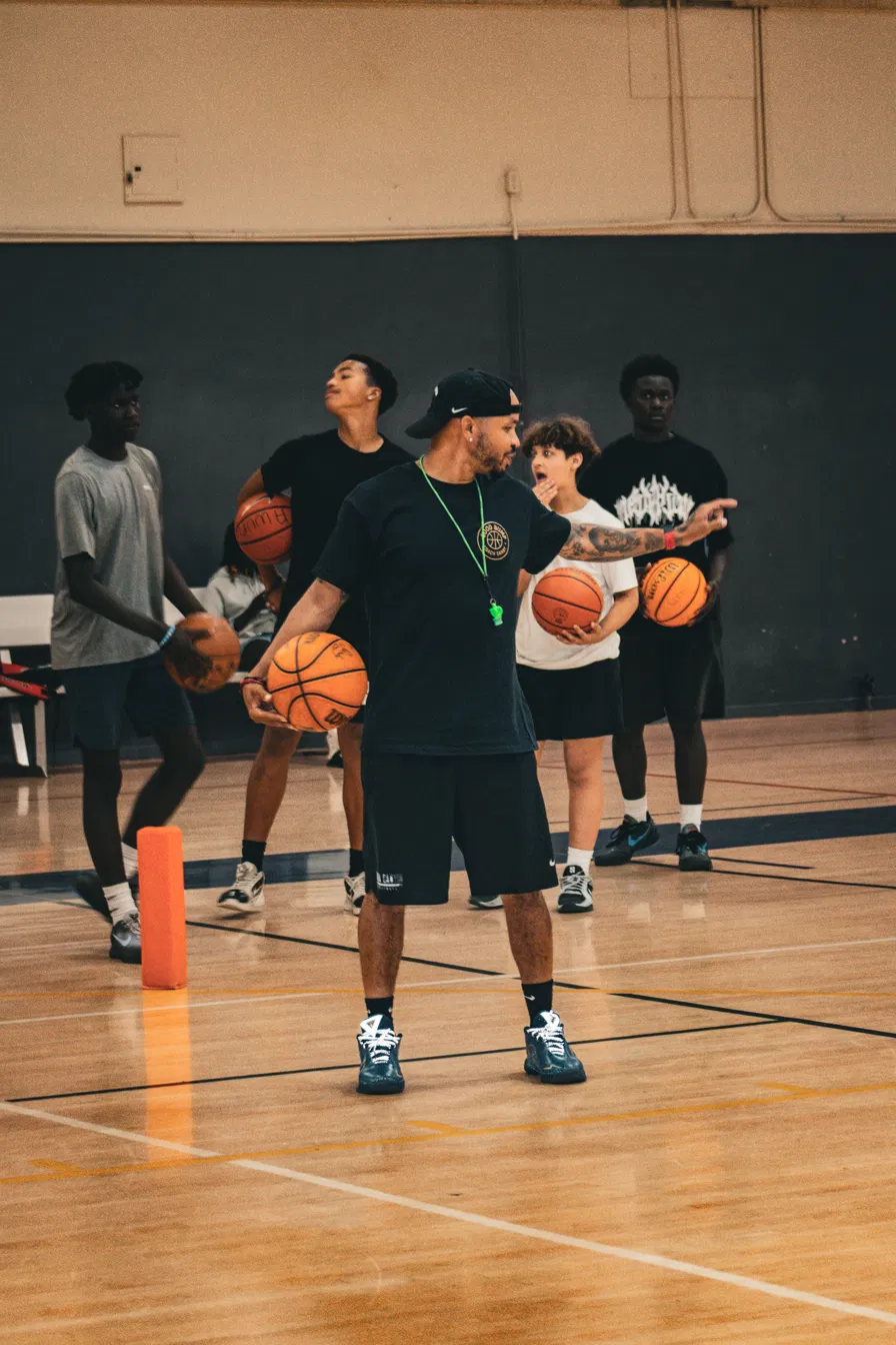 Coach Sandy directing players while holding a basketball during a drill