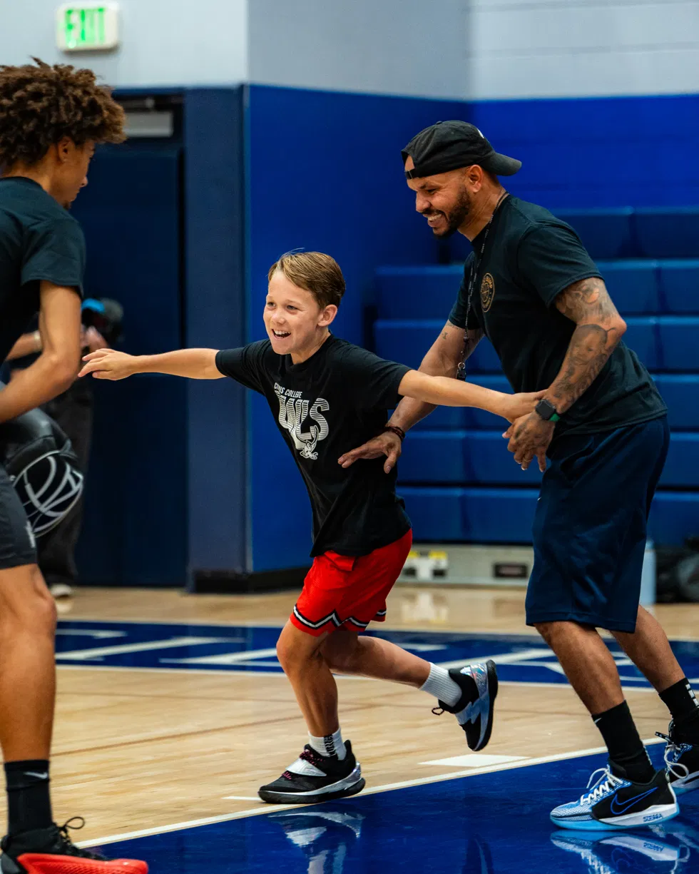 Coach Sandy working with a young player during a live drill in the gym