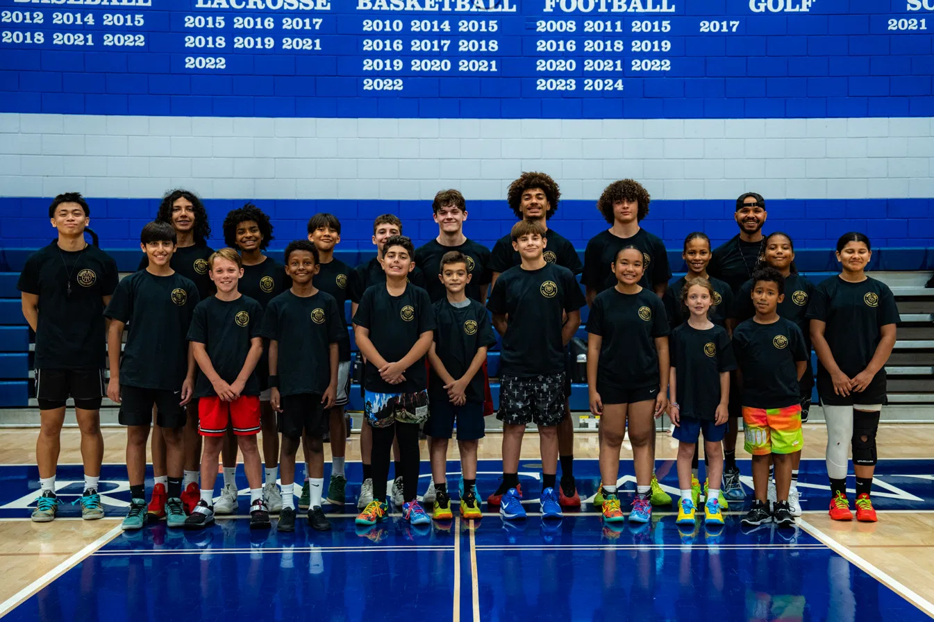 Group photo of clinic players and Coach Sandy lined up in the Sierra Canyon gym